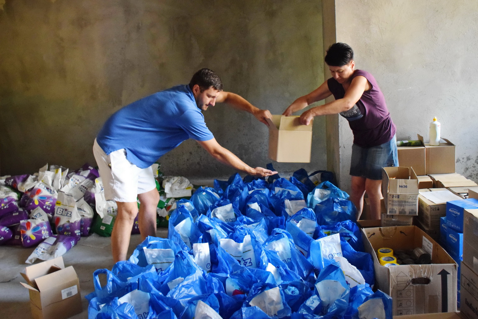Wolontariusze przygotowują paczki z artykułami spożywczymi oraz środkami higieny
